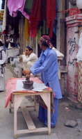 A fellow ironing with a hot coal iron for anyone who brings something.