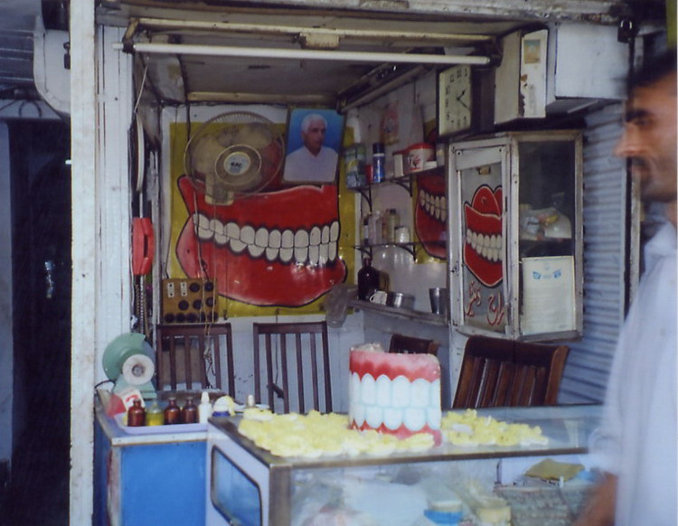 Another dentist, what you see is what you get, this is reception, examination room & store. The dentist usually sits in one of the kitchen chairs until he vacates to let the patient sit. The indistinct yellow things in the foreground are molds of people's mouths. 