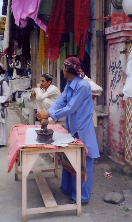 A fellow ironing with a hot coal iron for anyone who brings something.